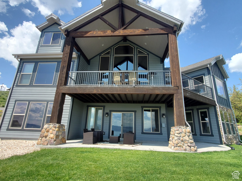 Back of house featuring a lawn, a balcony, and a patio