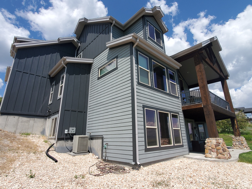 View of side of property featuring central air condition unit, a balcony, and board and batten siding
