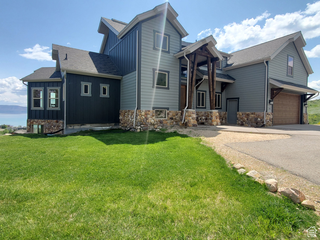 View of home\'s exterior featuring board and batten siding, concrete driveway, a garage, and a lawn