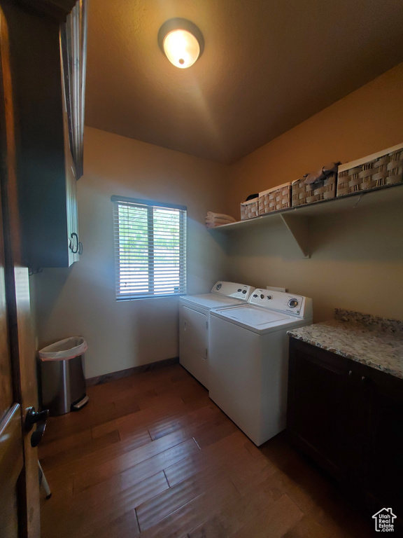 Washroom with washing machine and dryer, cabinet space, and wood finished floors