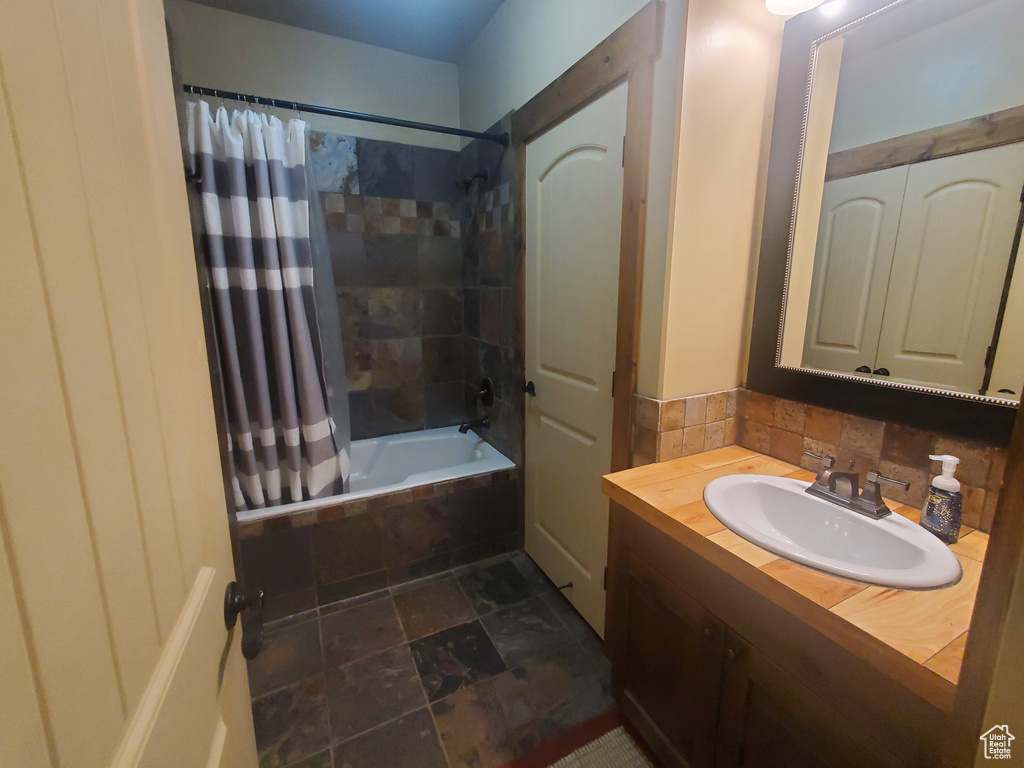 Bathroom featuring shower / tub combo with curtain, vanity, and backsplash