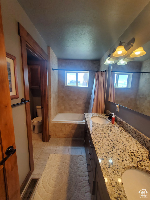 Full bath featuring plenty of natural light, toilet, vanity, and tile patterned floors
