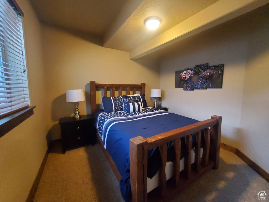 Carpeted bedroom with baseboards and multiple windows