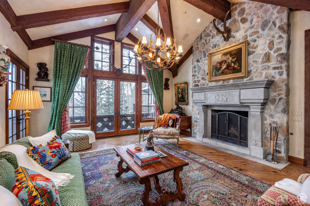 Living area featuring a chandelier, a fireplace, beam ceiling, high vaulted ceiling, and wood finished floors