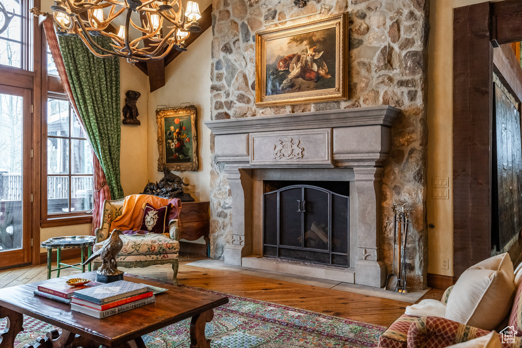 Living area featuring wood-type flooring, an inviting chandelier, and a fireplace