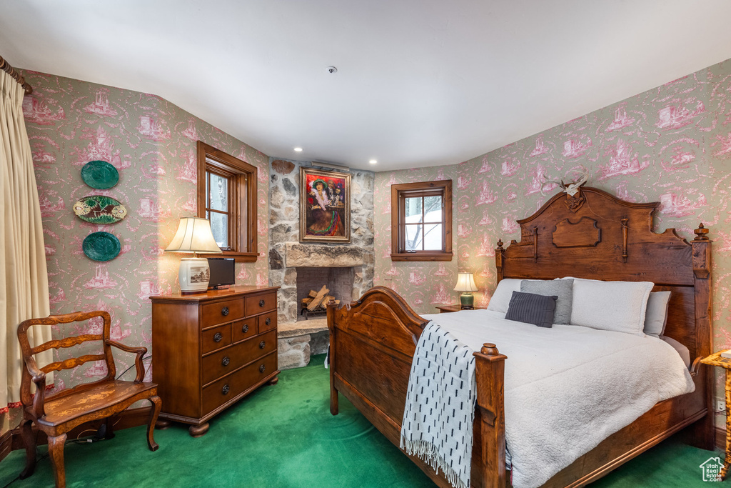 Carpeted bedroom featuring wallpapered walls and a fireplace