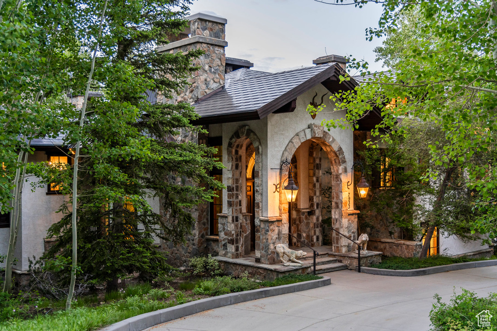 View of exterior entry with stone siding, stucco siding, and a chimney