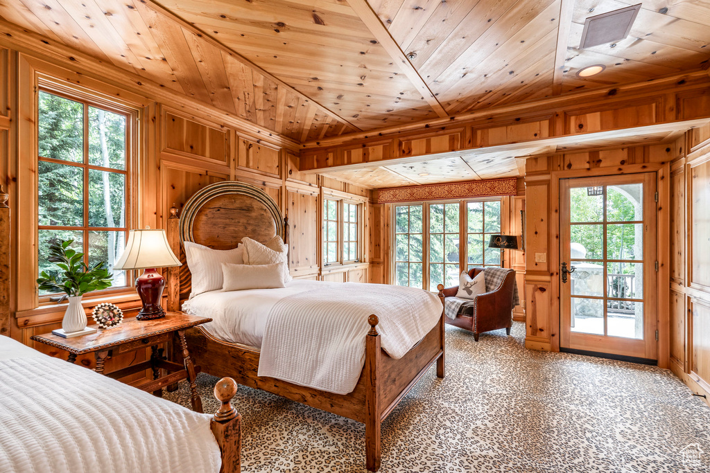 Carpeted bedroom with wood walls, access to exterior, and wood ceiling