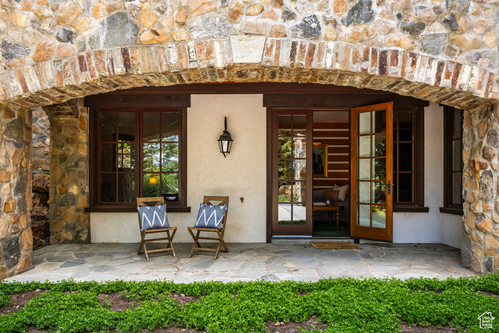Entrance to property with stone siding, stucco siding, and french doors