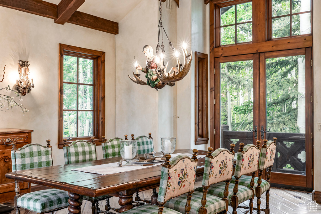 Dining room featuring plenty of natural light, a chandelier, beam ceiling, and a high ceiling