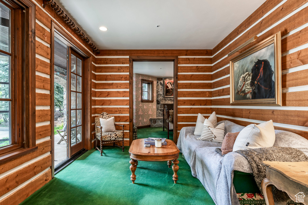 Living area featuring healthy amount of natural light, carpet floors, and wooden walls