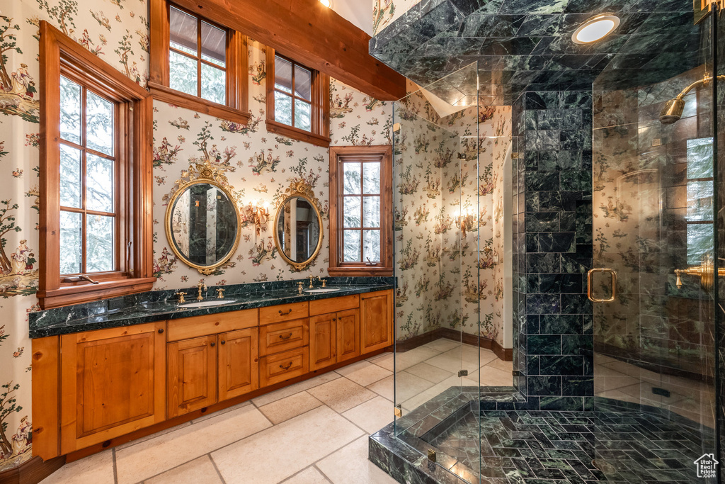 Full bathroom with a shower stall, wallpapered walls, double vanity, and a sink