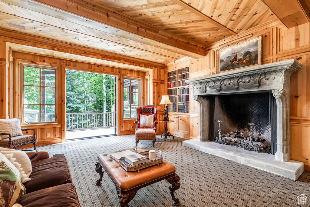Carpeted living room with a wood ceiling with exposed beams, wooden walls, a premium fireplace, a decorative wall, and built in features
