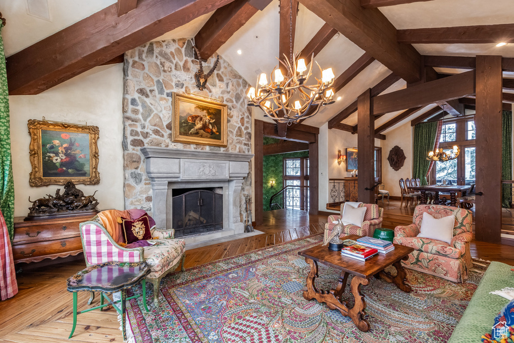 Living room with beam ceiling, plenty of natural light, an inviting chandelier, and a fireplace
