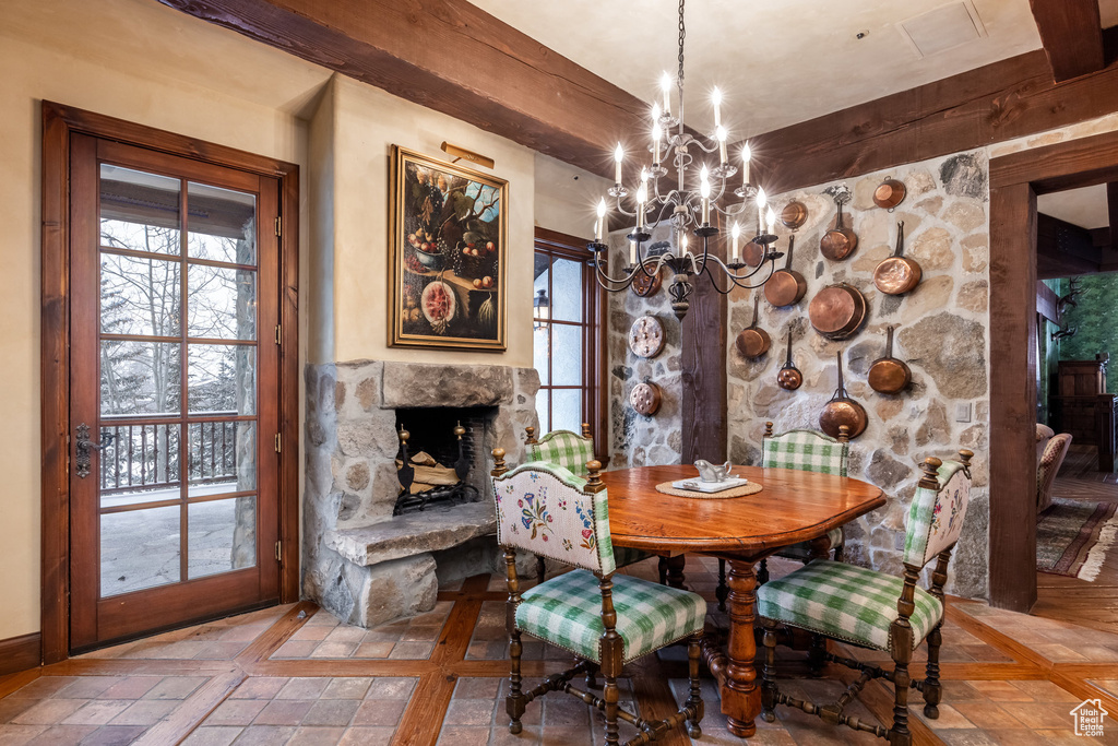 Dining area featuring beamed ceiling, a stone fireplace, and an inviting chandelier