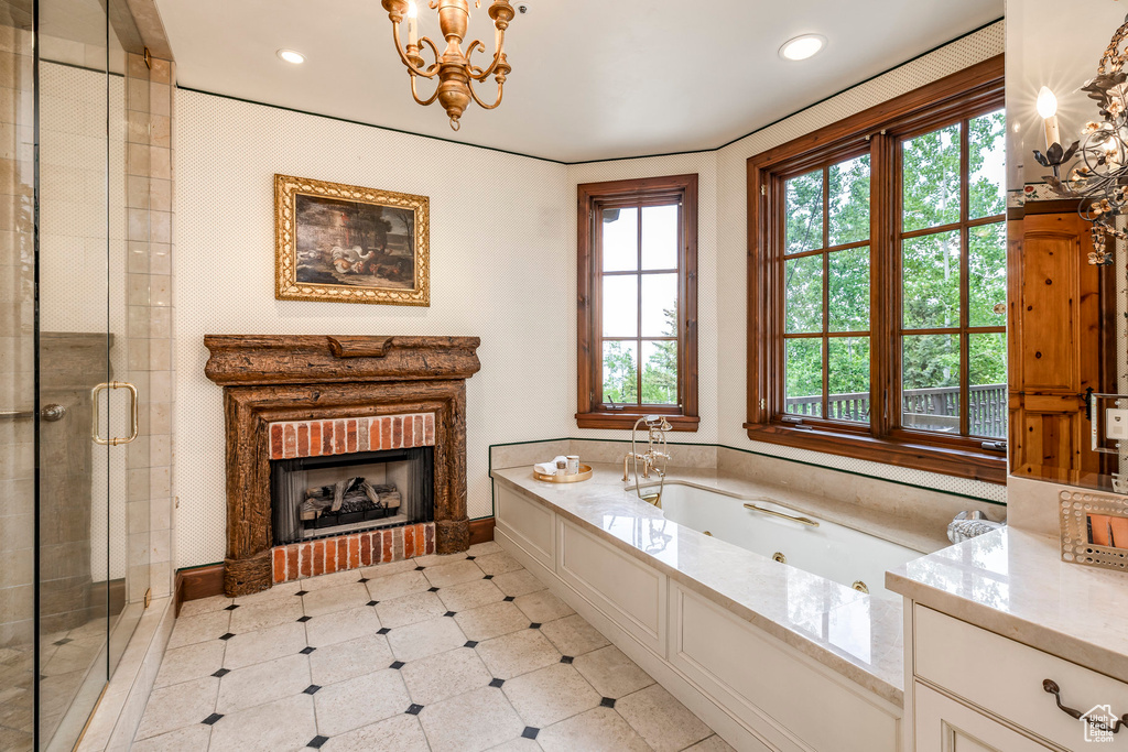 Bathroom with a tub with jets, a shower stall, a brick fireplace, a chandelier, and recessed lighting