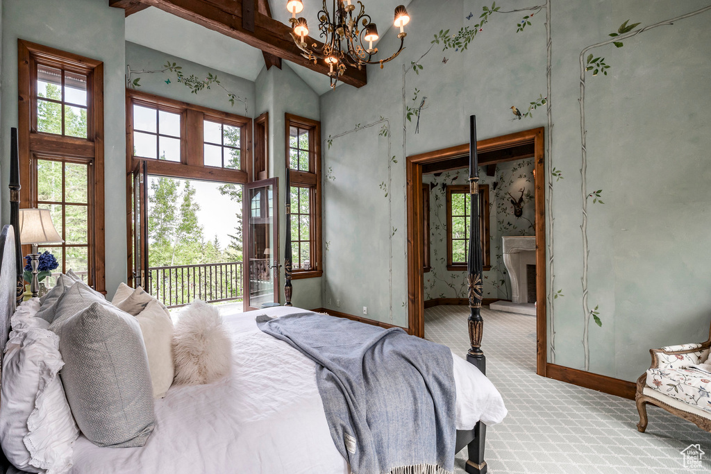 Carpeted bedroom with high vaulted ceiling, a chandelier, and access to outside