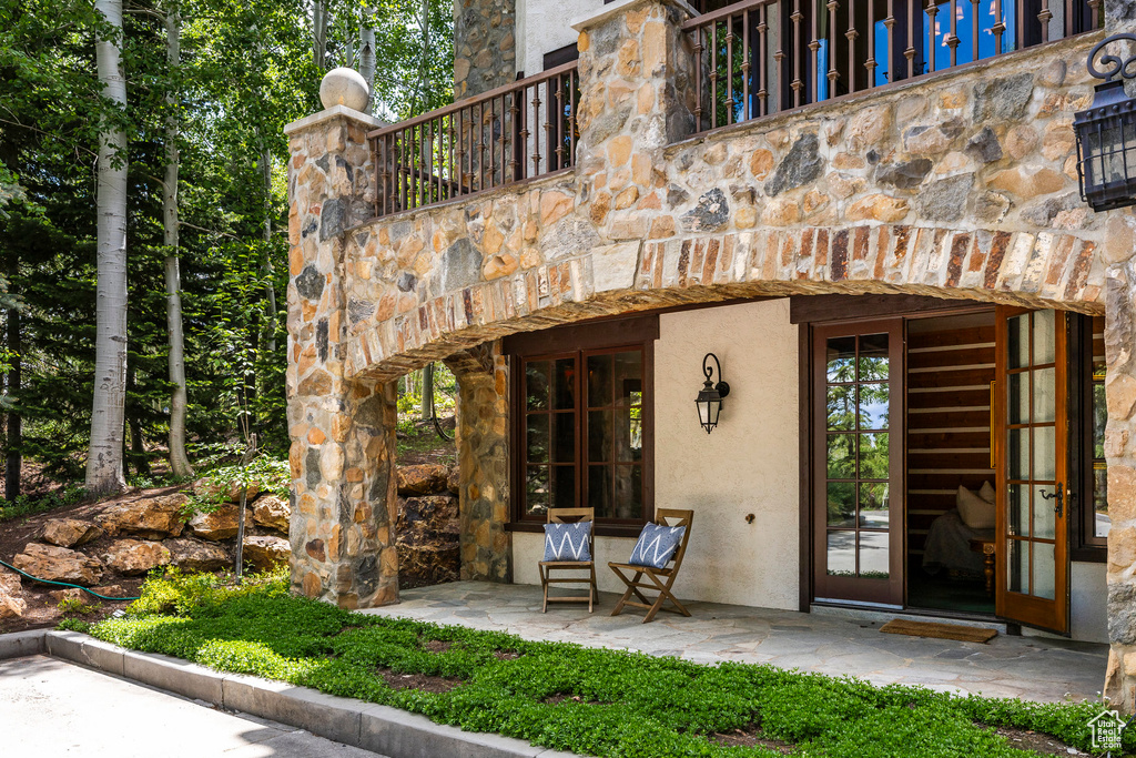 Doorway to property featuring stone siding, stucco siding, and french doors