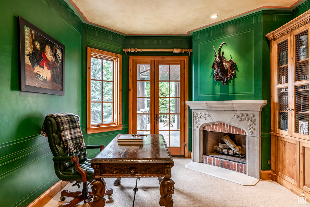 Home office with french doors, a fireplace, crown molding, a decorative wall, and carpet