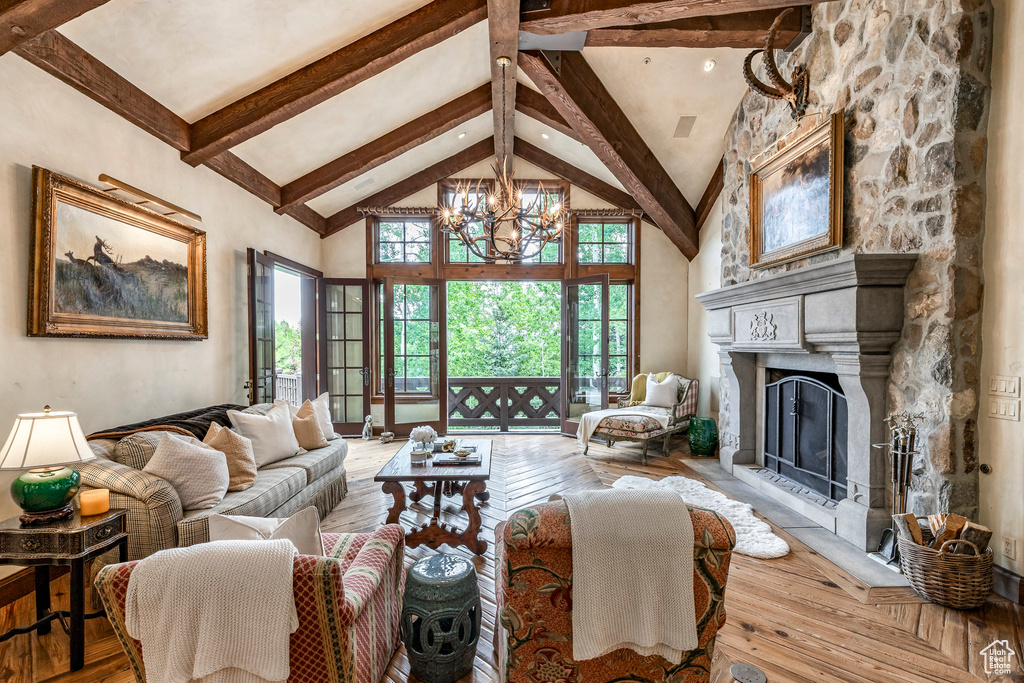 Living room with beam ceiling, a chandelier, high vaulted ceiling, wood-type flooring, and a fireplace with raised hearth