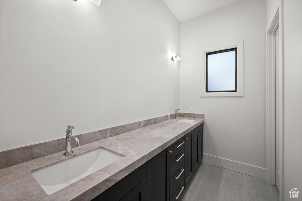 Full bath with double vanity, baseboards, and tile patterned floors