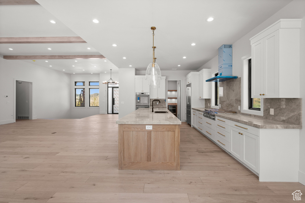 Kitchen featuring premium range hood, open floor plan, stainless steel appliances, a sink, and tasteful backsplash