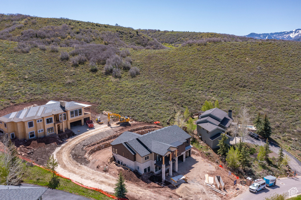 Aerial view of property and surrounding area with a forest and a mountainous background
