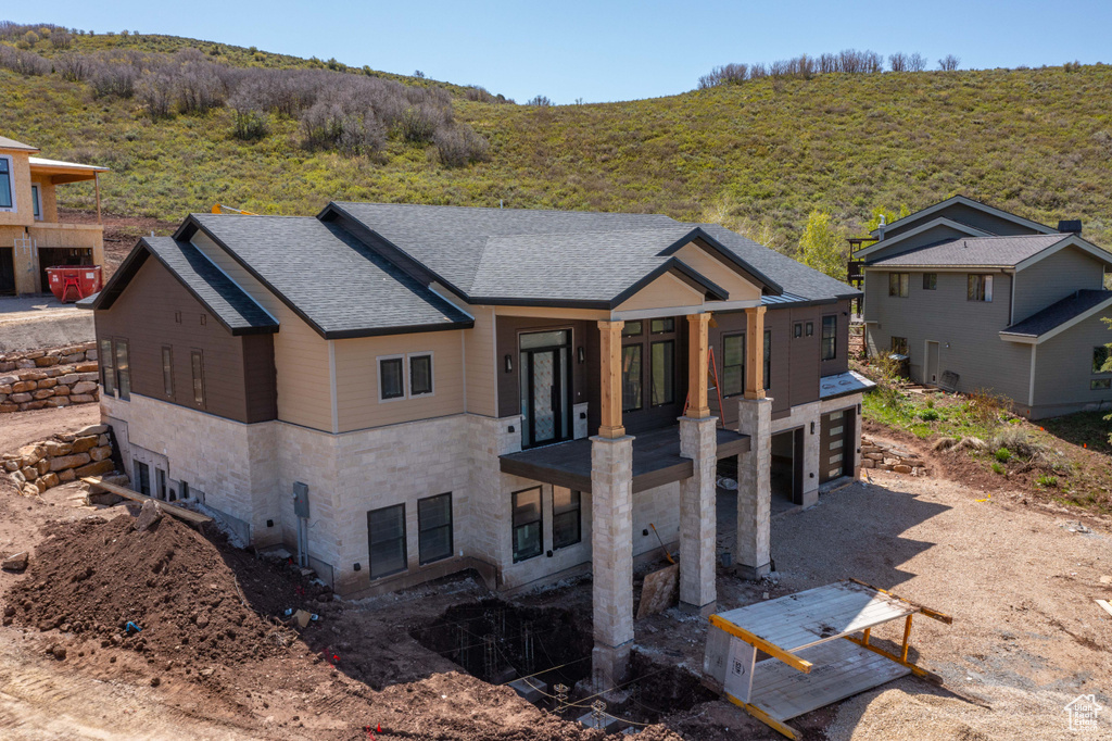 View of front of home with stone siding and roof with shingles
