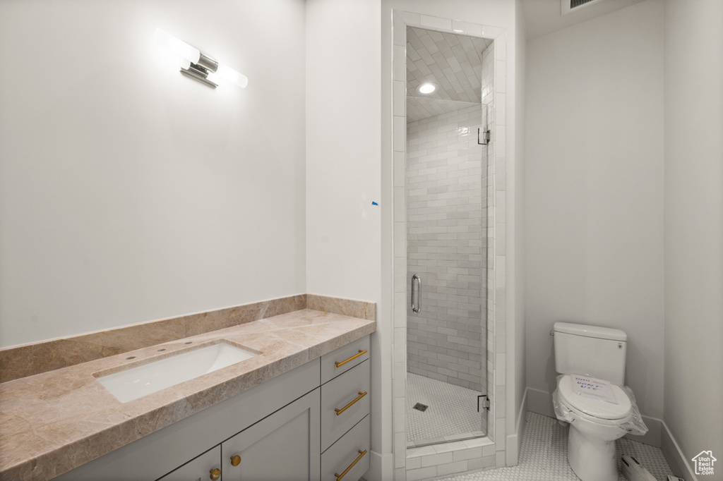 Full bath with a sink, a stall shower, toilet, and tile patterned floors