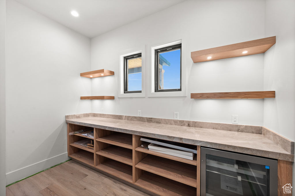 Indoor dry bar with beverage cooler, light wood-type flooring, baseboards, and recessed lighting