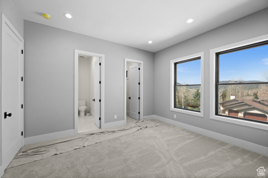 Unfurnished bedroom featuring recessed lighting, baseboards, carpet floors, and ensuite bath