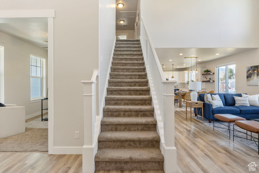 Stairs with baseboards, wood finished floors, and recessed lighting