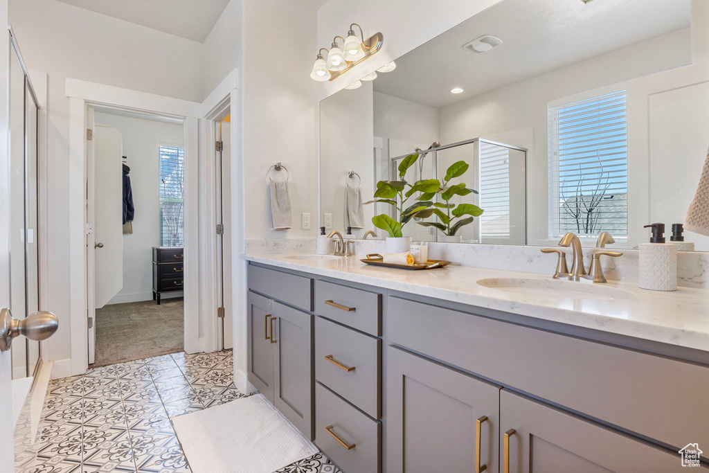 Full bathroom featuring a stall shower, tile patterned flooring, a sink, and double vanity