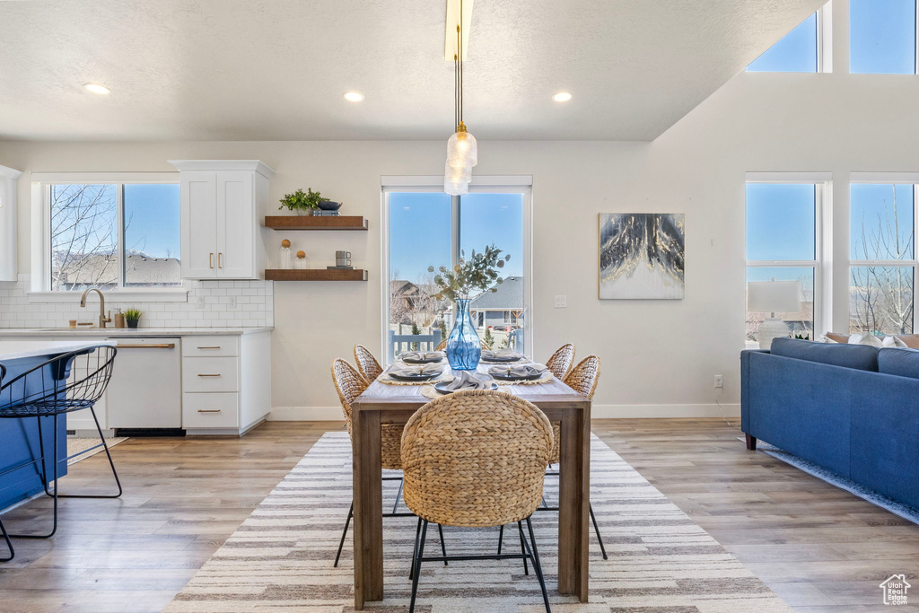 Dining area featuring light wood finished floors, baseboards, a textured ceiling, and recessed lighting