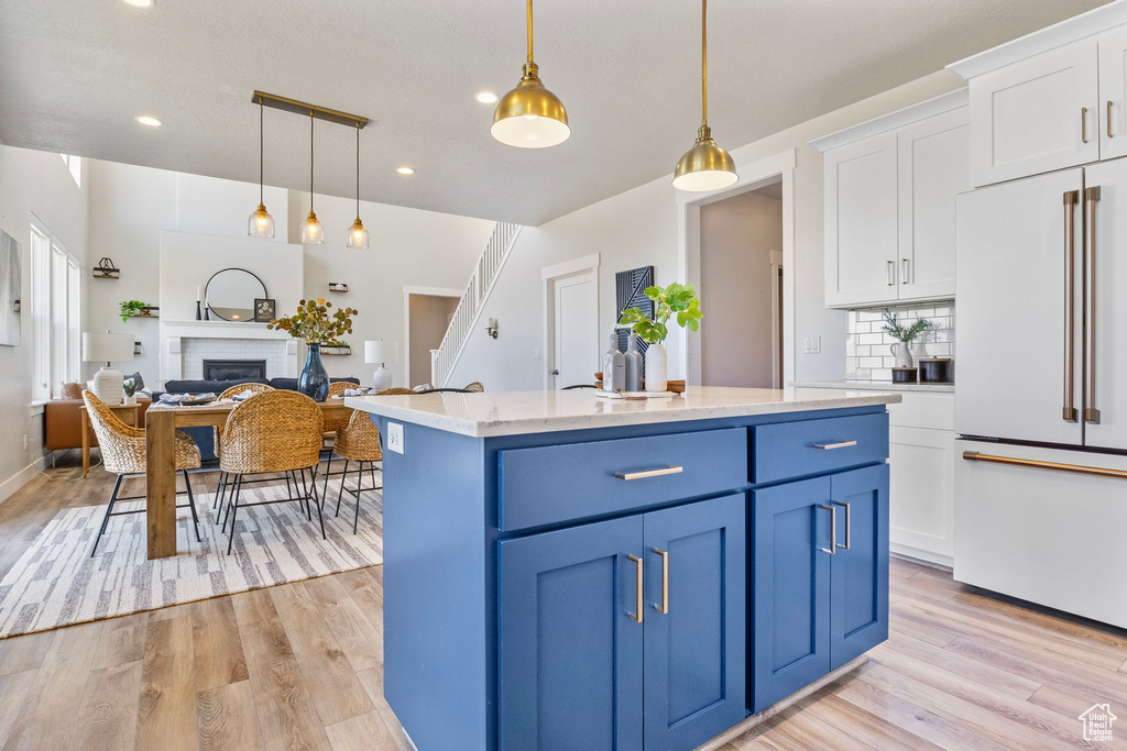 Kitchen featuring blue cabinetry, white cabinetry, light wood finished floors, and high end white fridge