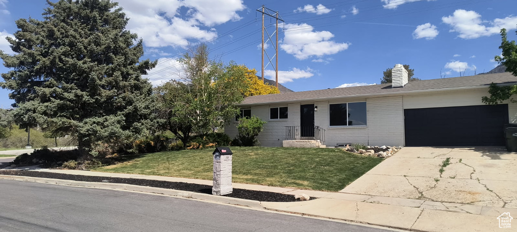 Single story home with a garage, a front lawn, concrete driveway, a chimney, and brick siding