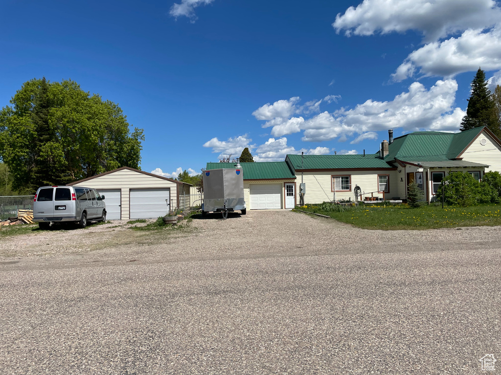 View of front facade with a garage, metal roof, and an outbuilding