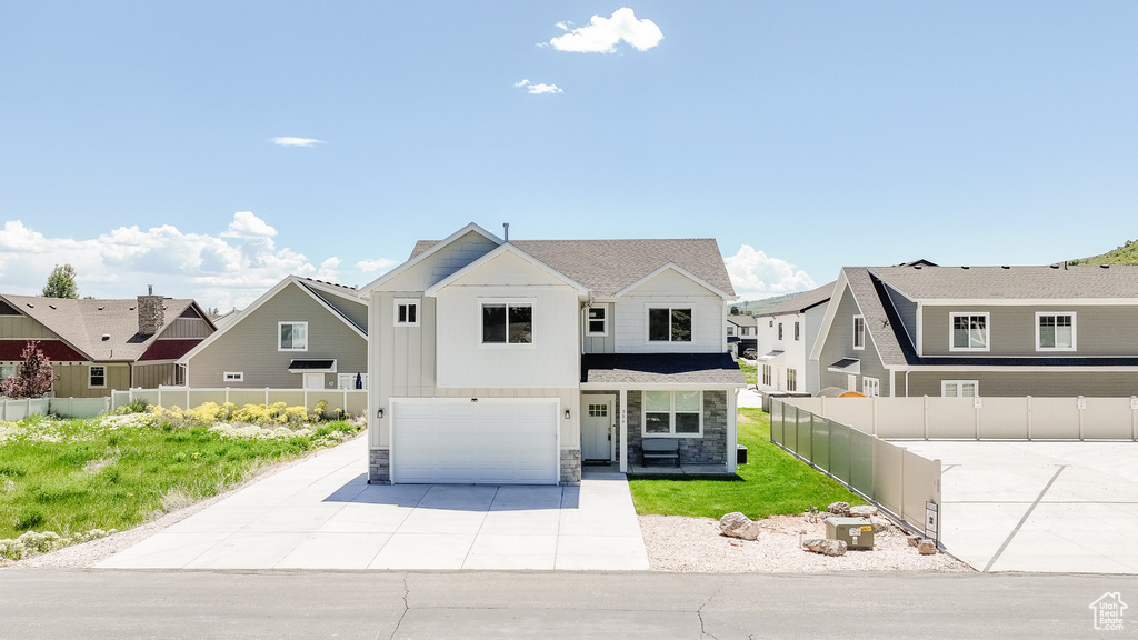 View of front of home with a garage, driveway, stone siding, and a residential view