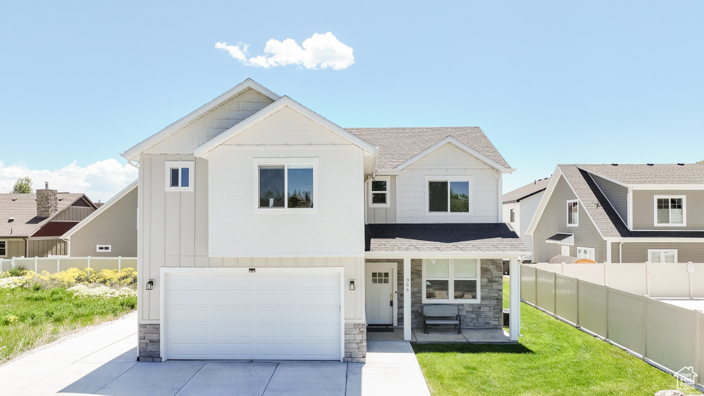 View of front of property with stone siding, driveway, and a porch