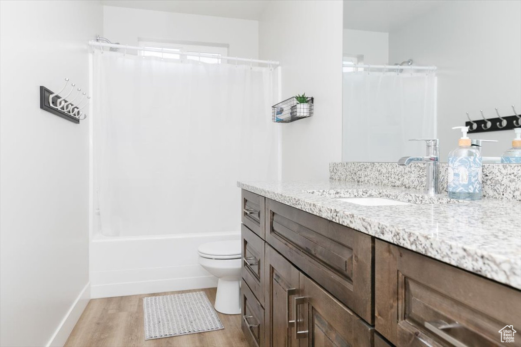 Full bathroom featuring hardwood / wood-style flooring, vanity, toilet, and shower / bath combination with curtain