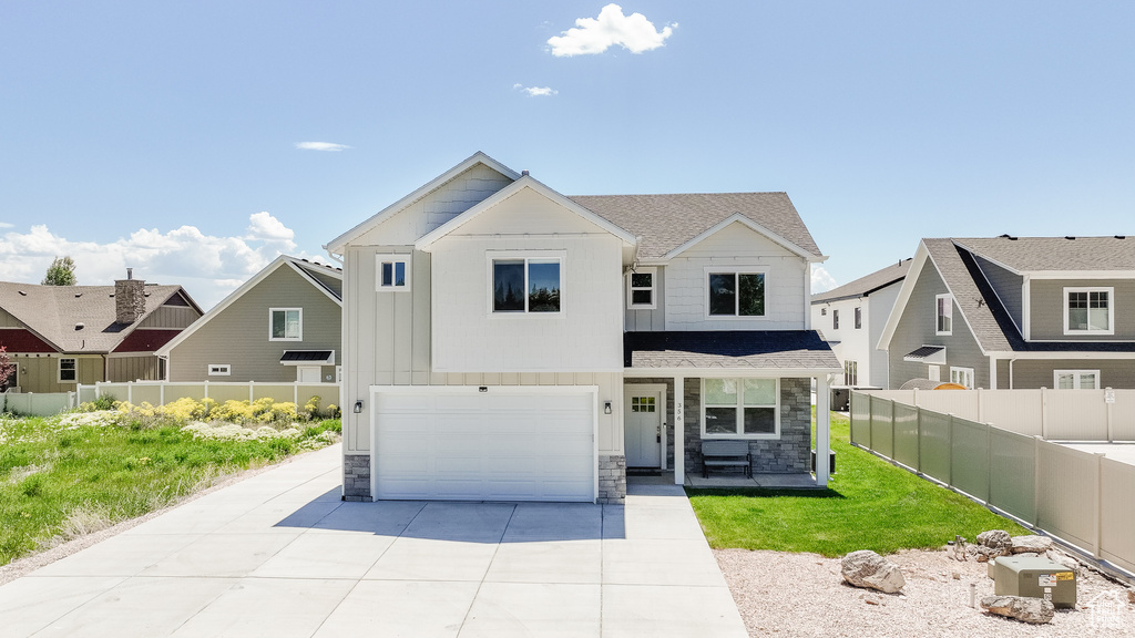 View of front of property with stone siding, concrete driveway, an attached garage, covered porch, and a shingled roof