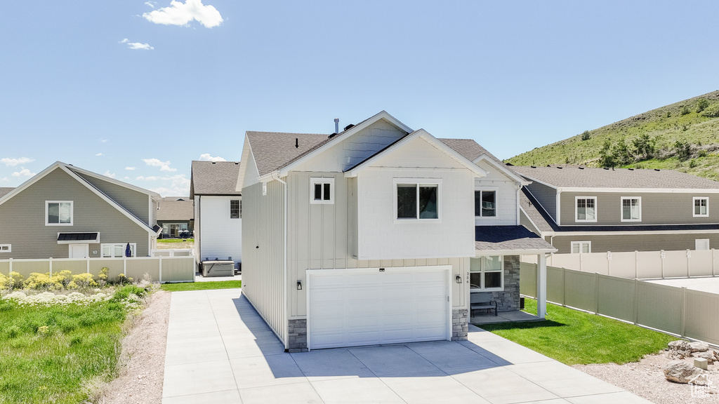View of front of home with an attached garage, stone siding, board and batten siding, and driveway