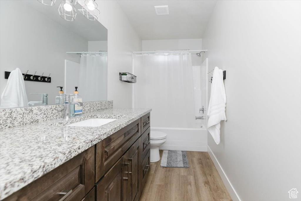 Full bathroom with shower / tub combo with curtain, vanity, toilet, and hardwood / wood-style floors