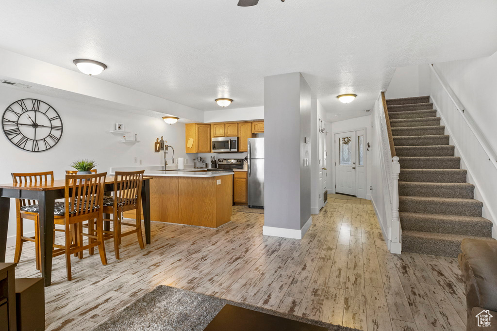 Kitchen featuring stainless steel appliances, kitchen peninsula, and light wood-type flooring