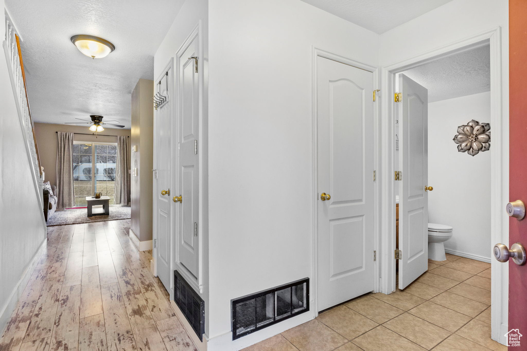 Hallway with light tile patterned flooring and a textured ceiling