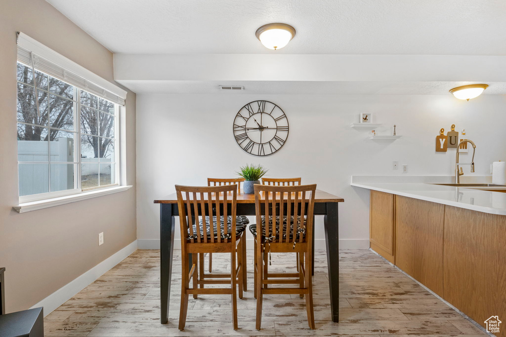 Dining space with sink and light wood-type flooring