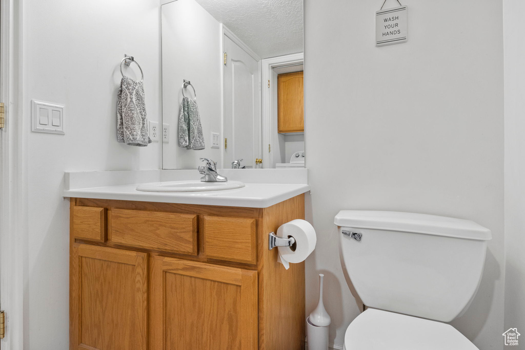 Bathroom with vanity, toilet, and a textured ceiling