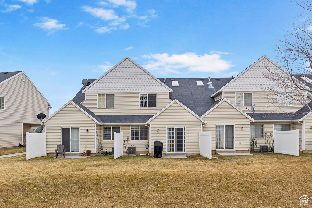 Back of property featuring central AC unit, a lawn, and a patio