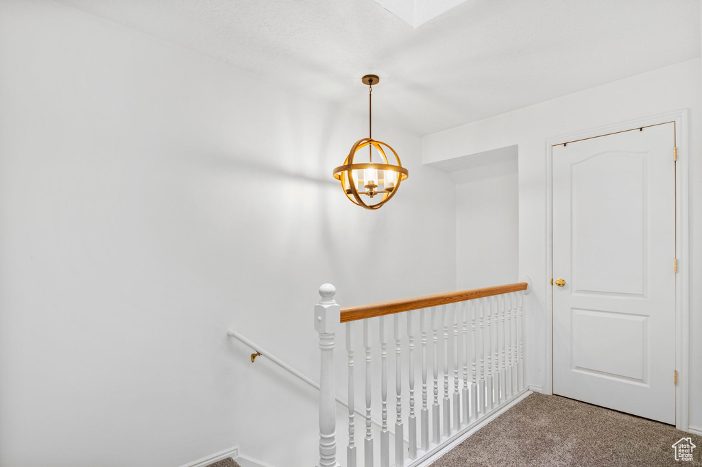 Stairway featuring carpet and a notable chandelier