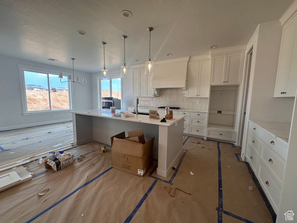 Kitchen featuring custom range hood, backsplash, white cabinetry, light countertops, and a textured ceiling